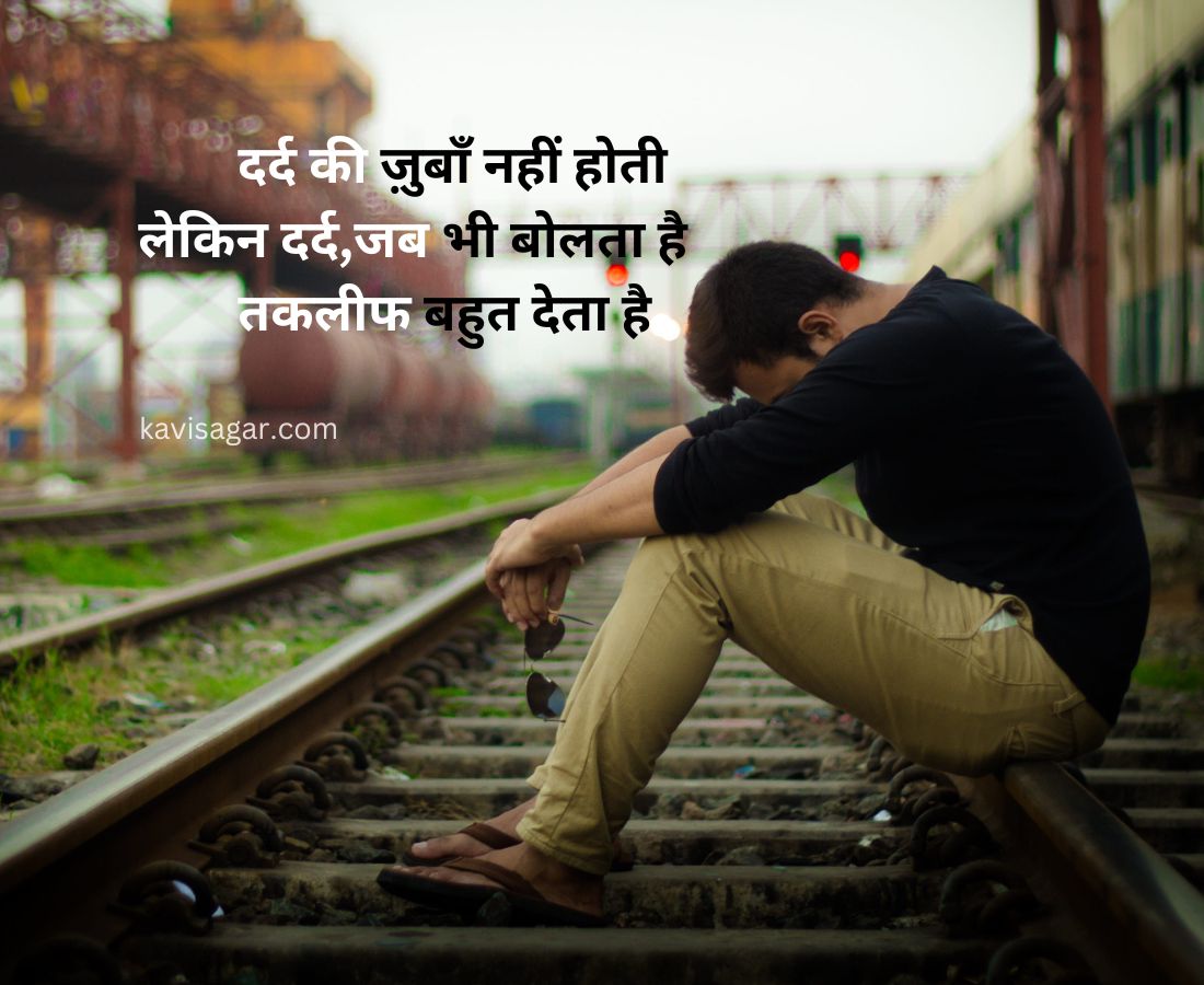 A lonely man sitting on a train track with his head bowed, and there are trains on the another track.